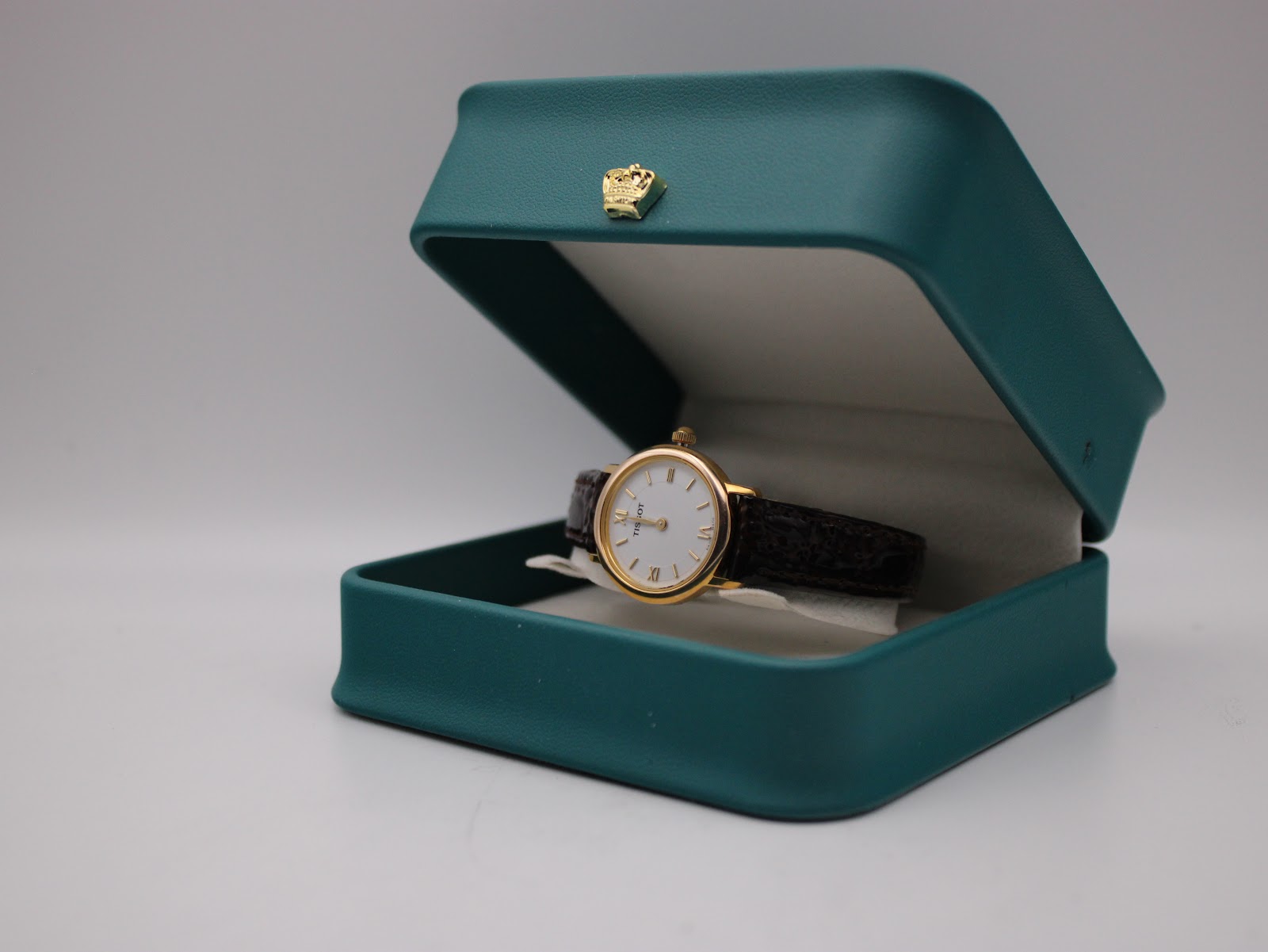The Tissot C225K watch displayed in an open teal presentation box with a gold crown emblem on the lid.