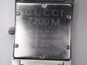 Close-up of the watch case back, clearly showing "GUCCI 7700 M", "SWISS MADE", "STAINLESS STEEL", "WATER RESISTANT", "3 ATM", and serial number "0028986" engravings.