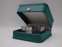The Gucci 7700 M watch presented in an open, generic teal watch box with a gold crown emblem.
