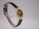 Opposite angled side view of the Gucci 6000L watch on a clear stand, showing the watch's elegant curves.