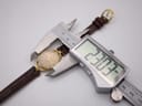 Digital caliper measuring the case diameter of the Gucci 6000L watch, showing a precise reading of 23.07mm.