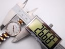 Top-down view of the watch case being measured by a digital caliper, showing 26.66 mm diameter.