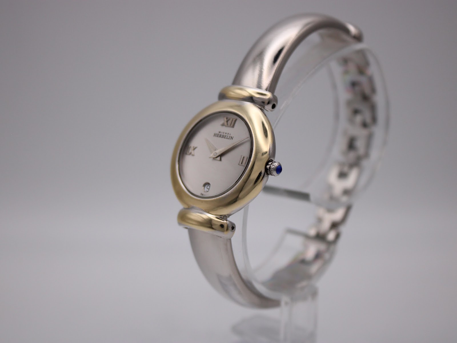 Angled view of Michel Herbelin 16836.B watch showing two-tone case, silver dial, and integrated bangle bracelet.