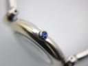 Macro shot of the watch crown, featuring a prominent blue cabochon.