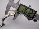 Digital caliper measuring the watch case diameter at 26.12mm, with the watch visible.