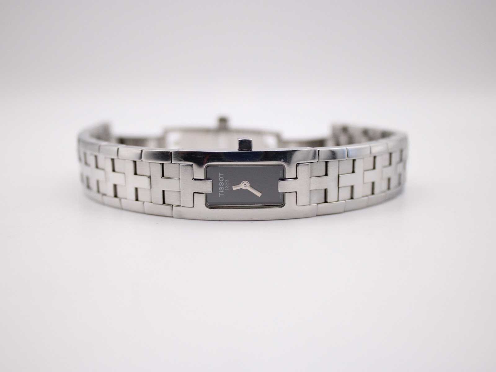 Front view of the Tissot L820P watch lying flat, showcasing the rectangular black dial and the full integrated stainless steel bracelet.