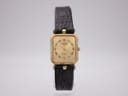 Front view of Raymond Weil rectangular gold electroplated watch with champagne dial and black Roman numerals on a white background.