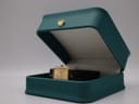 The Raymond Weil watch resting inside an open, empty teal-coloured watch display box.
