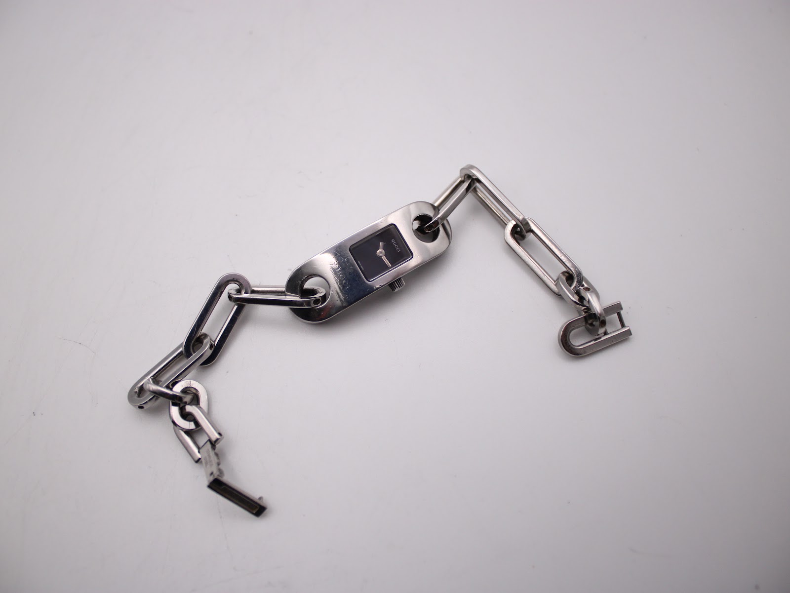 Overhead view of the Gucci 6100L watch and its integrated chain-link bracelet laid flat.