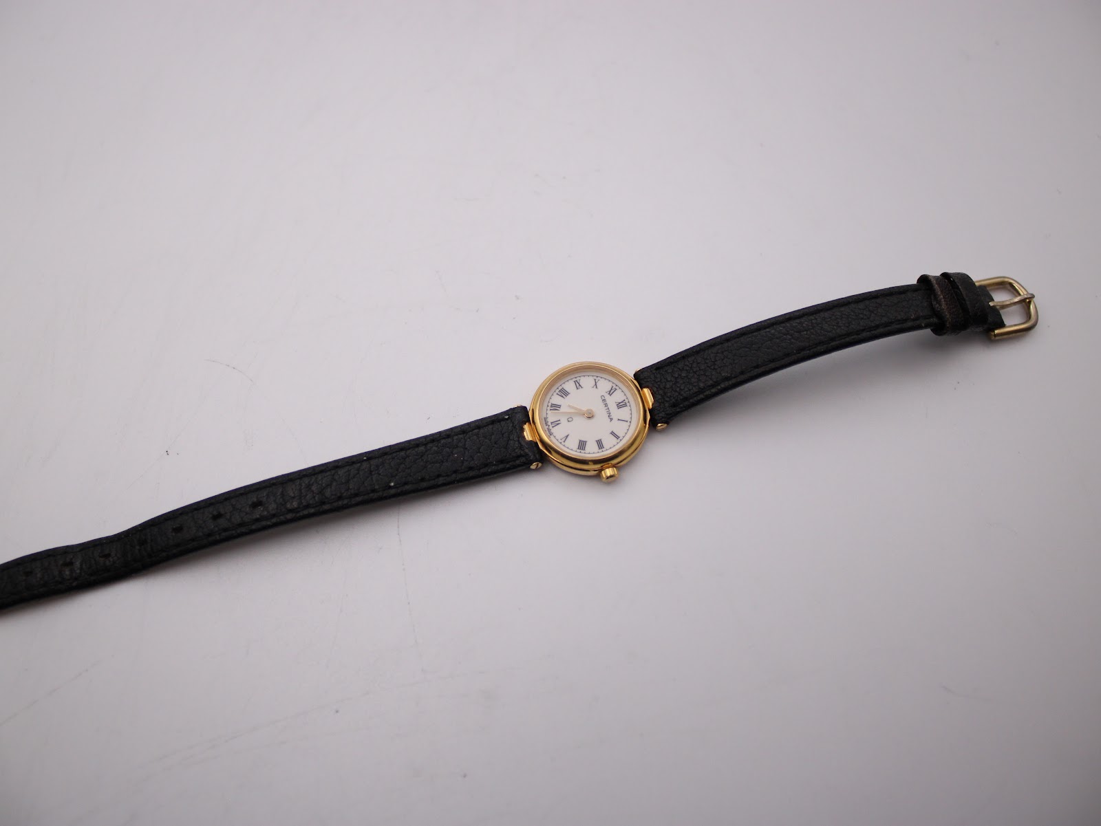 Full view of Certina watch on black leather strap, laid flat.