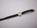 Full view of Certina watch on black leather strap, laid flat.