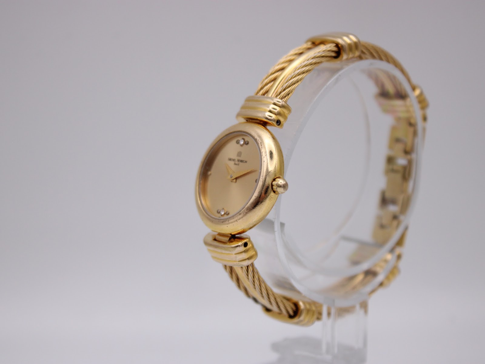 Angled left side view of the Michel Herbelin watch, highlighting the twisted cable bracelet design.