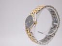 Side view of the Manin Cartear watch on a stand, showing the textured bezel and gold crown.