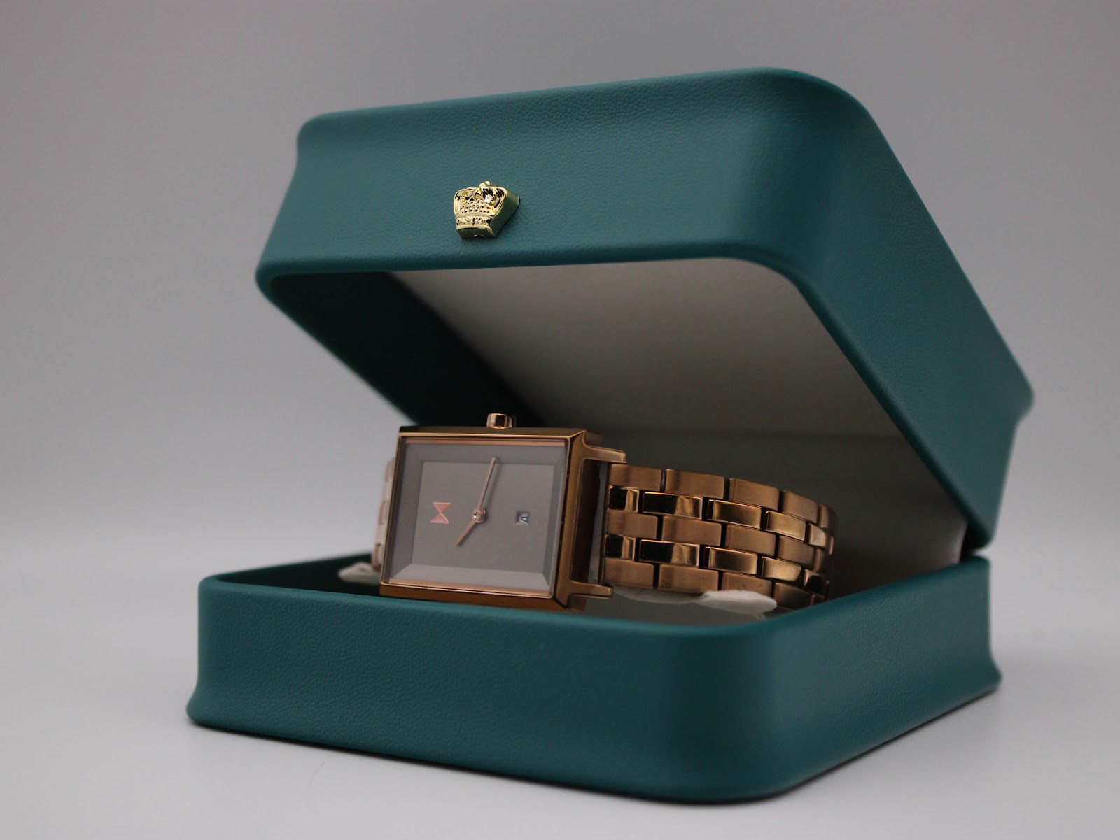Angled view of the MVMT Signature Square watch presented in a decorative teal watch box with a gold crown emblem.