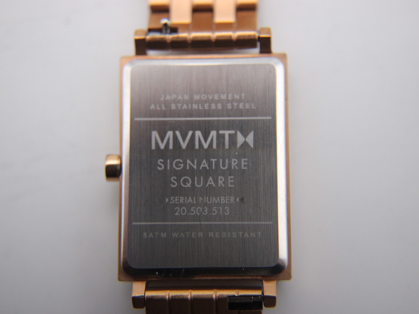Close-up of the brushed stainless steel case back, showing 'MVMT Signature Square', serial number, 'Japan Movement', 'All Stainless Steel', and '5ATM Water Resistant' engravings.