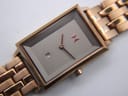 Detail shot of the MVMT Signature Square dark brown dial, rose gold MVMT logo, hands, and date window at 4 o'clock.
