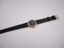 Full length view of the Raymond Rone watch laid flat, displaying the black leather strap and gold-tone buckle.