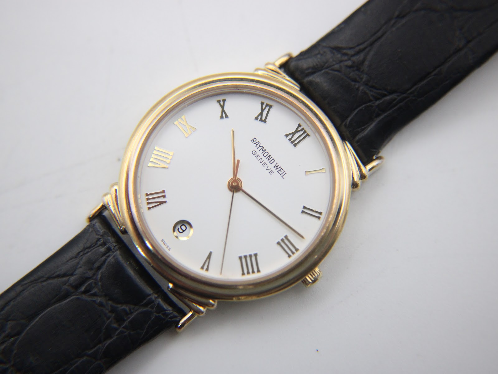 Overhead angled view of the Raymond Weil dial, showing the date window at 6 o'clock and gold hands.