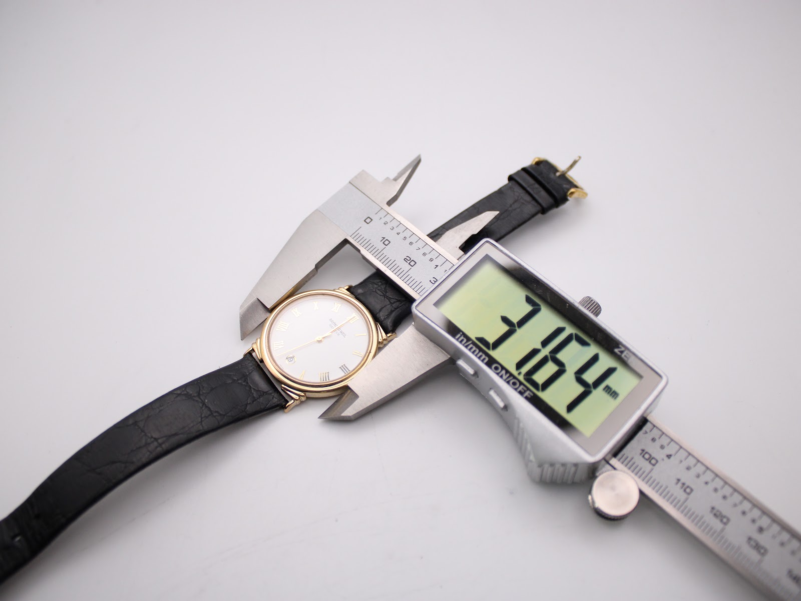 Digital caliper measuring the watch case diameter, showing 31.64mm on the display.