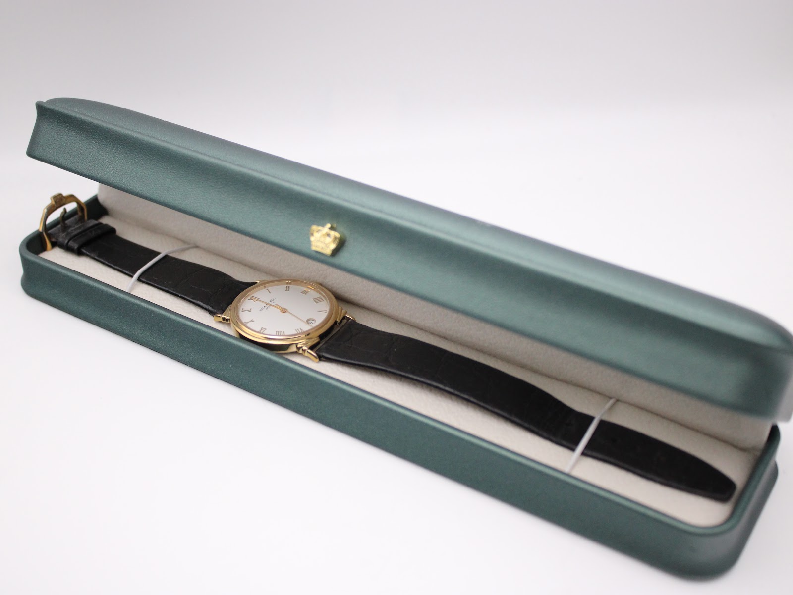 Raymond Weil watch with its black leather strap displayed inside a green presentation box.