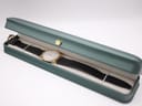 Raymond Weil watch with its black leather strap displayed inside a green presentation box.