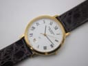Overhead angled view of the Jean Perret QJ watch dial, brown leather strap, and gold-tone buckle.