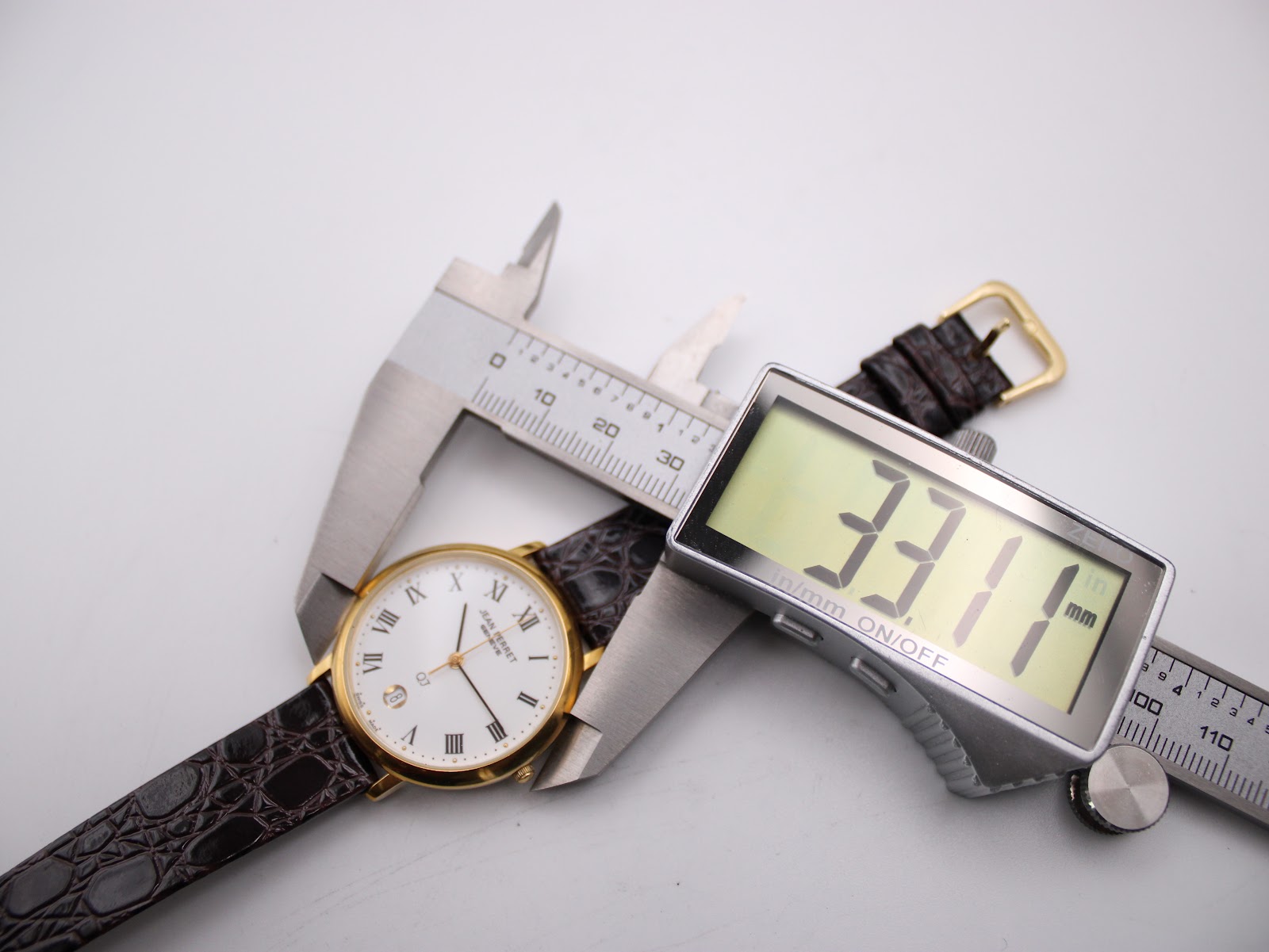 Close-up of the Jean Perret QJ watch being measured by a digital caliper, displaying a case size of 33.1mm.