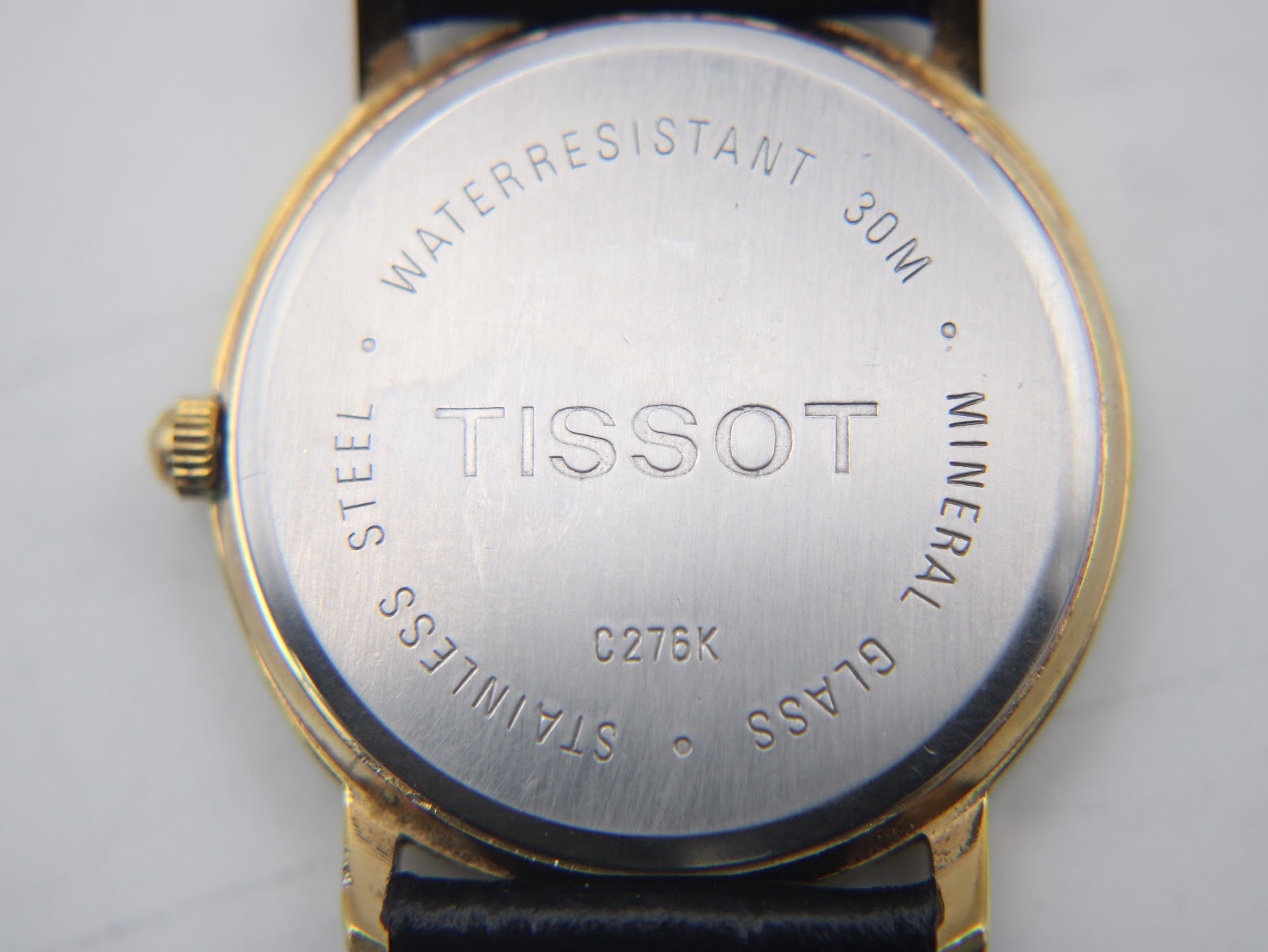 Close-up of the stainless steel case back with "TISSOT C276K", "WATERRESISTANT 30M", "STEEL", "MINERAL GLASS" engravings.