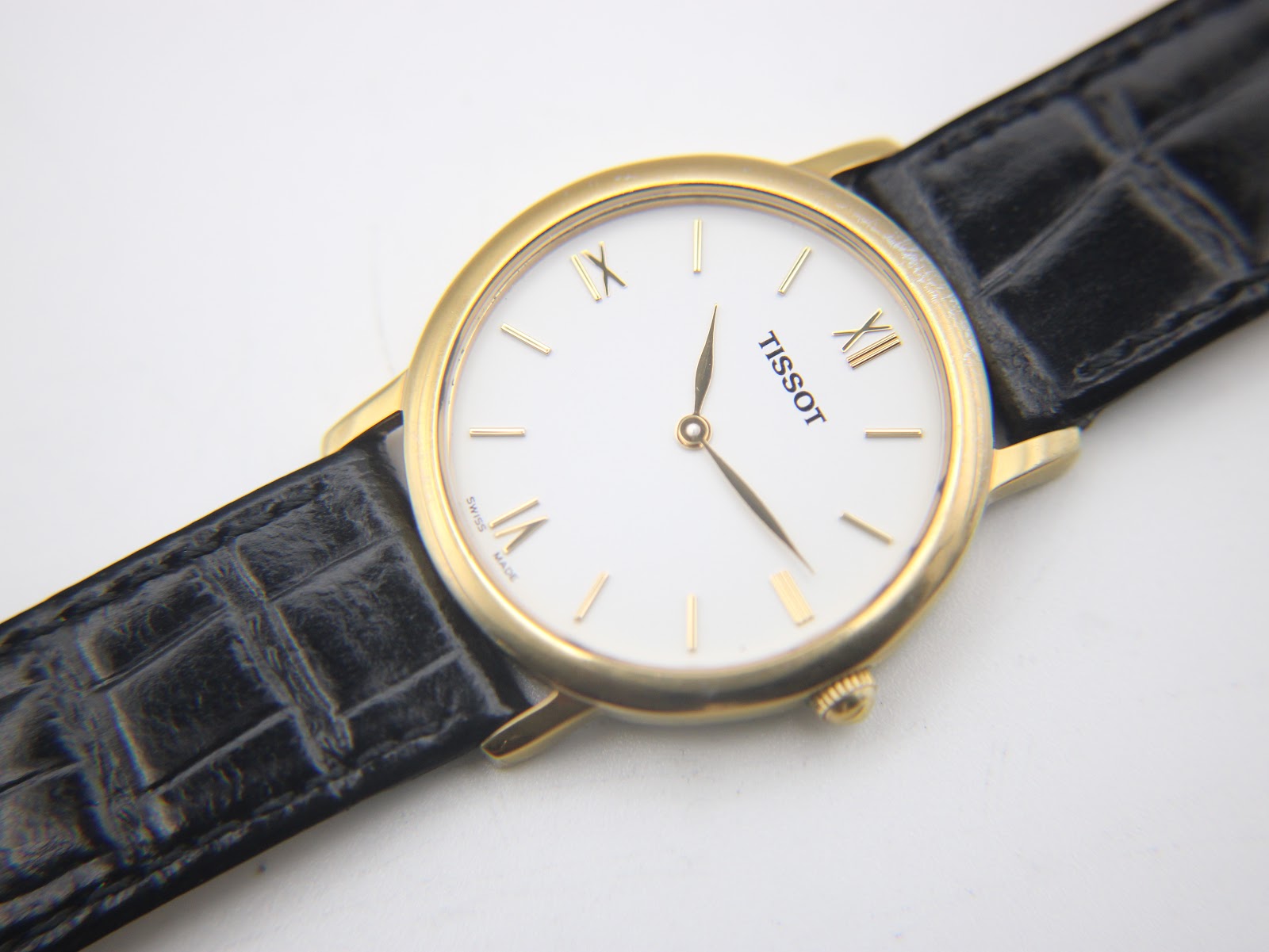 Diagonal close-up of the Tissot dial, showing Roman numerals, baton indices, and the TISSOT logo.