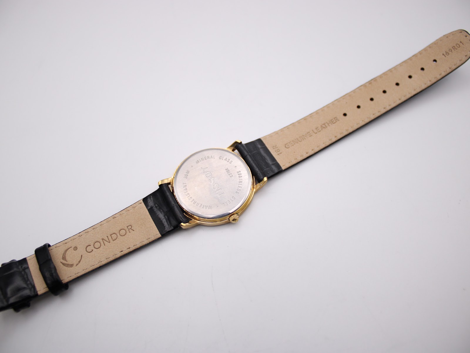 View of the watch from the back, showing the case back and the inside of the black leather strap with "CONDOR" and "GENUINE LEATHER" markings.