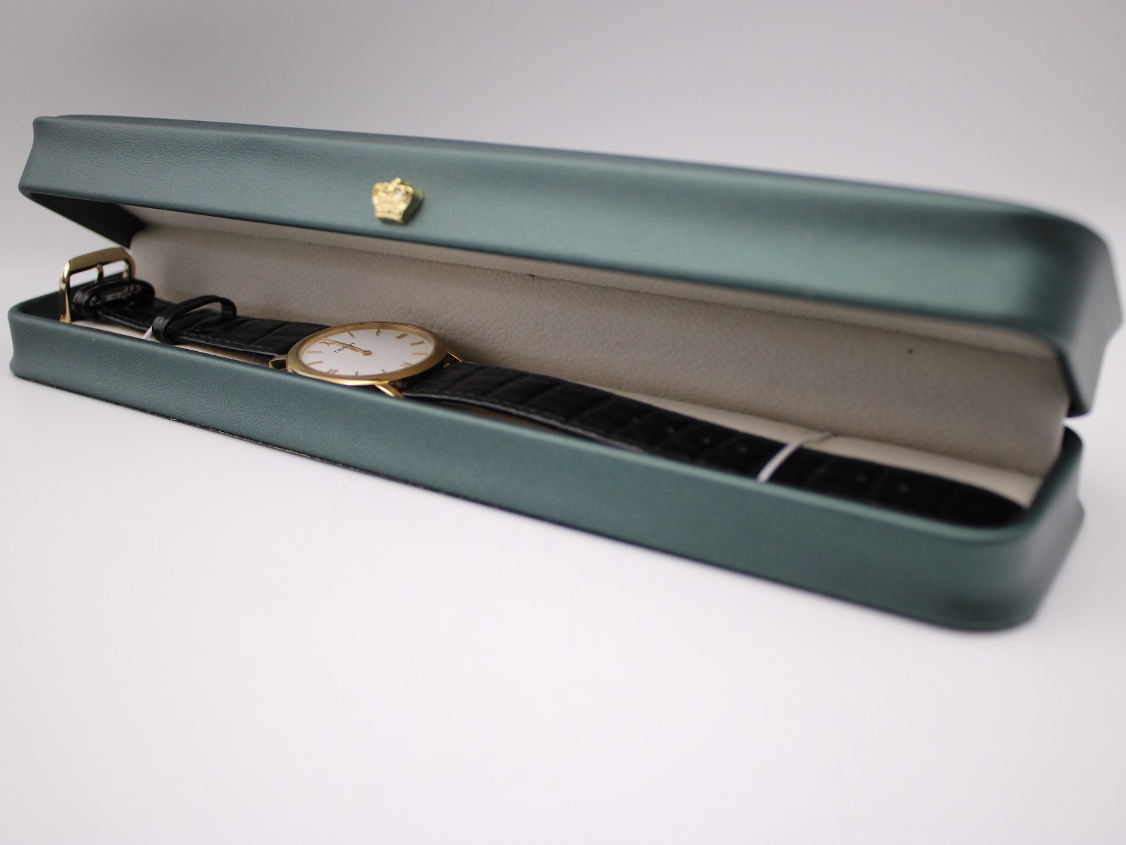The Tissot watch placed inside a dark green presentation box with a gold crown emblem.