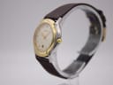 Angled side view of the Gucci watch, showing the polished gold-plated bezel and stainless steel case with the crown.