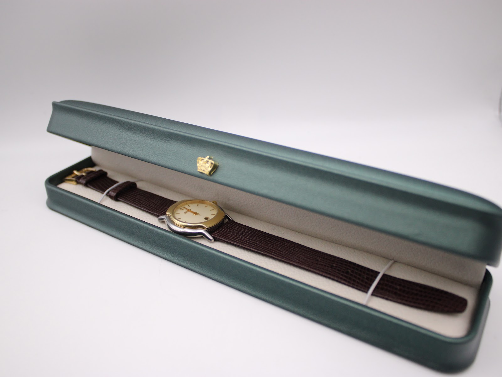 The Gucci watch presented inside a generic green display box with a cream interior.