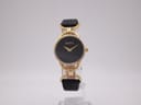 Front view of the Gucci 6000.2.L watch with a black dial, gold-tone case, and black textured leather strap on a clear stand.