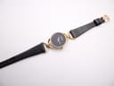 Full top-down view of the Gucci watch with its black textured leather strap extended on a white background.