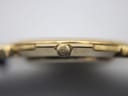 Macro close-up of the side of the watch case, focusing on the gold-tone crown embossed with the Gucci interlocking Gs logo.