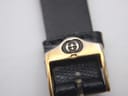 Close-up of the gold-tone pin buckle on the black leather strap, clearly showing the embossed Gucci interlocking Gs logo.