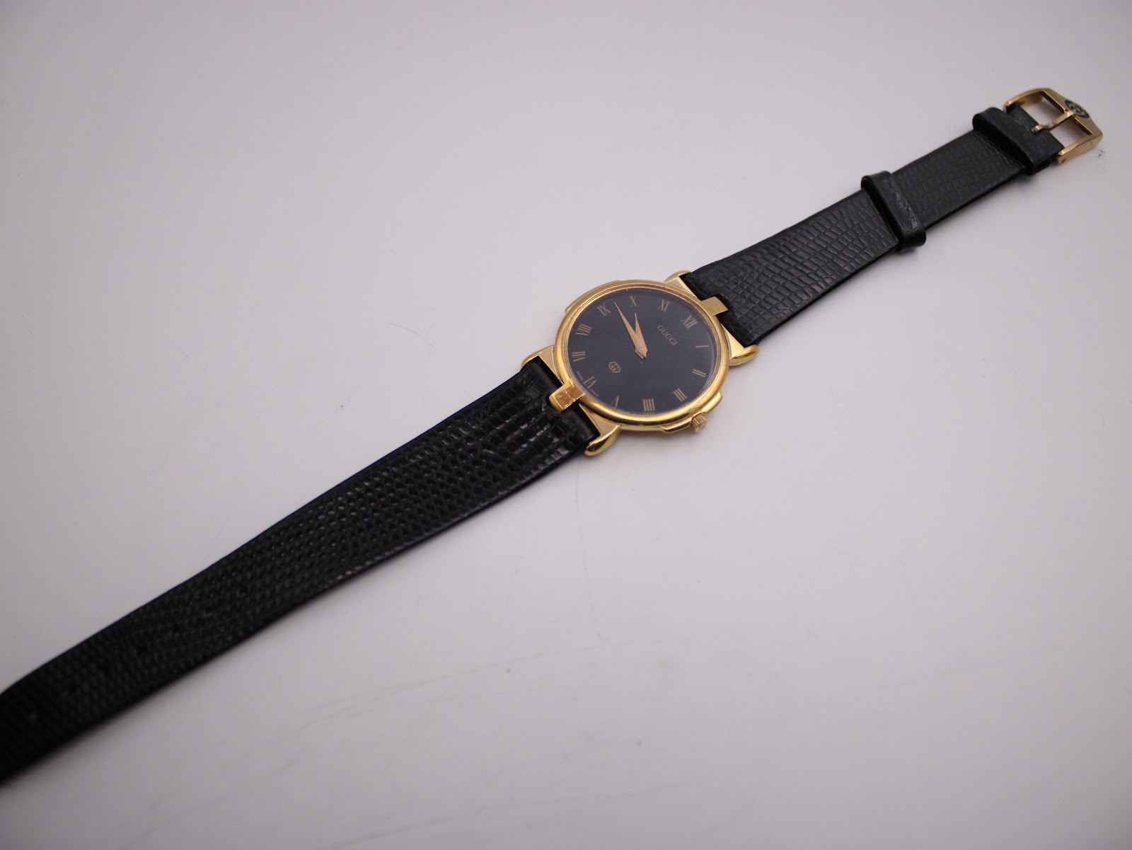 Full length view of the Gucci 3400M watch with its black leather strap extended, displayed on a white surface.