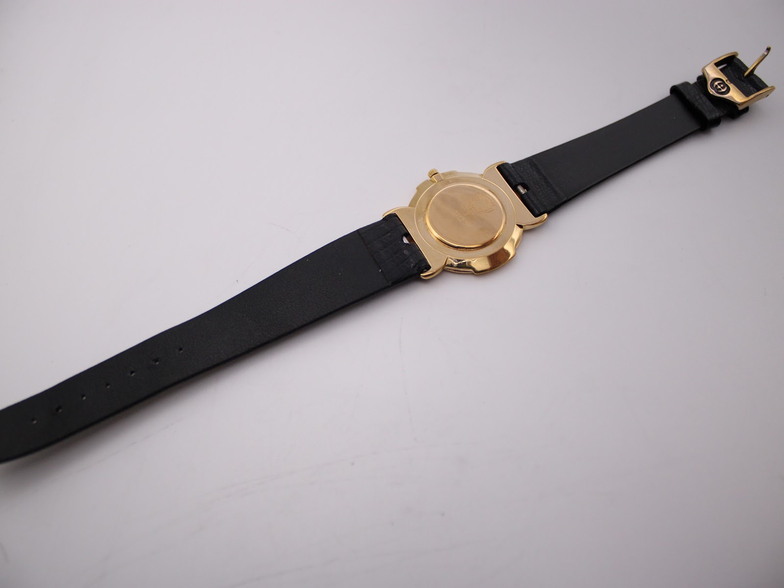 Full length back view of the Gucci 3400M watch with its black leather strap extended, showing the case back and strap reverse.