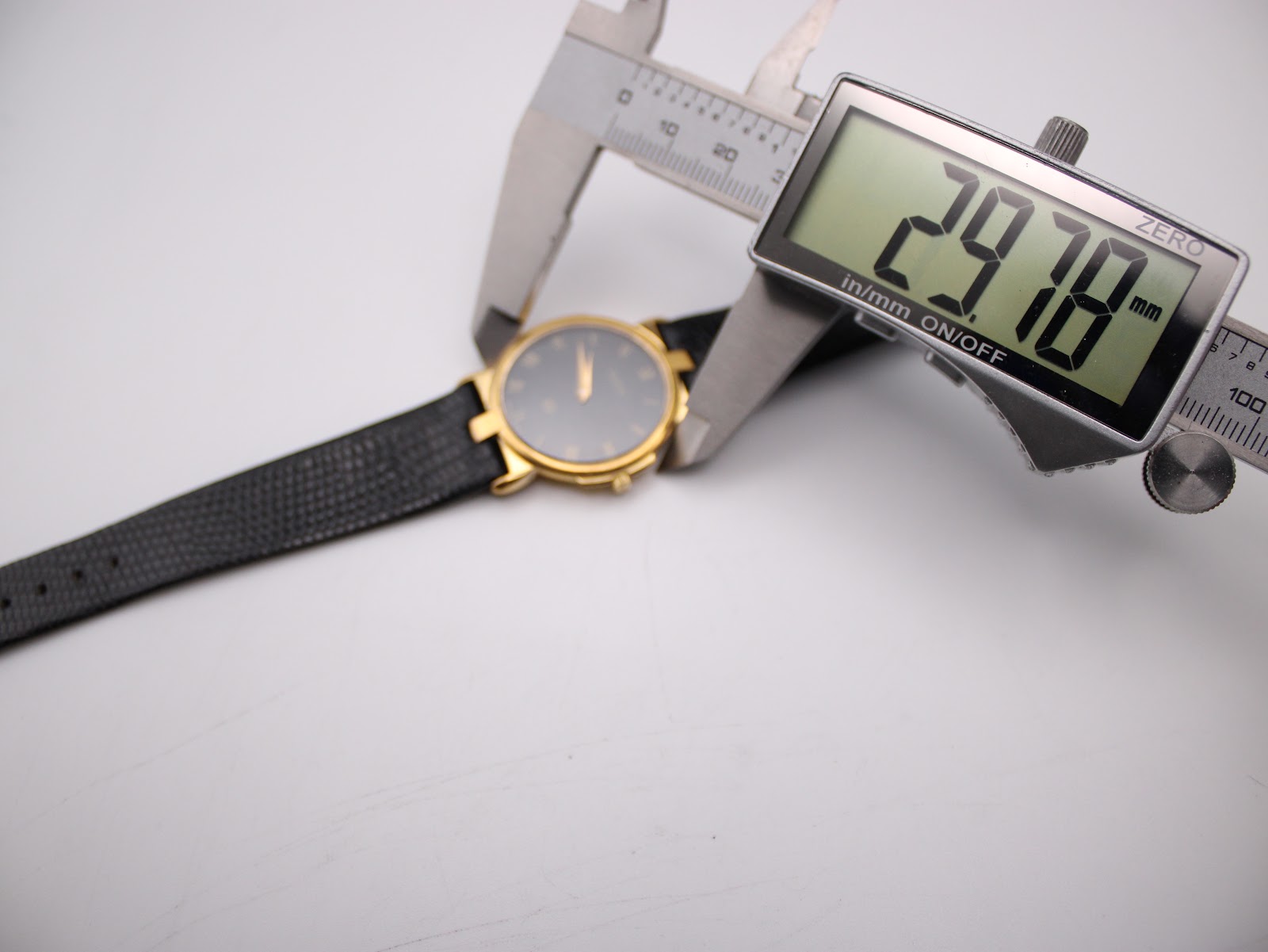 Digital caliper measuring the case diameter of the Gucci 3400M watch, displaying an exact measurement of 29.78 mm.