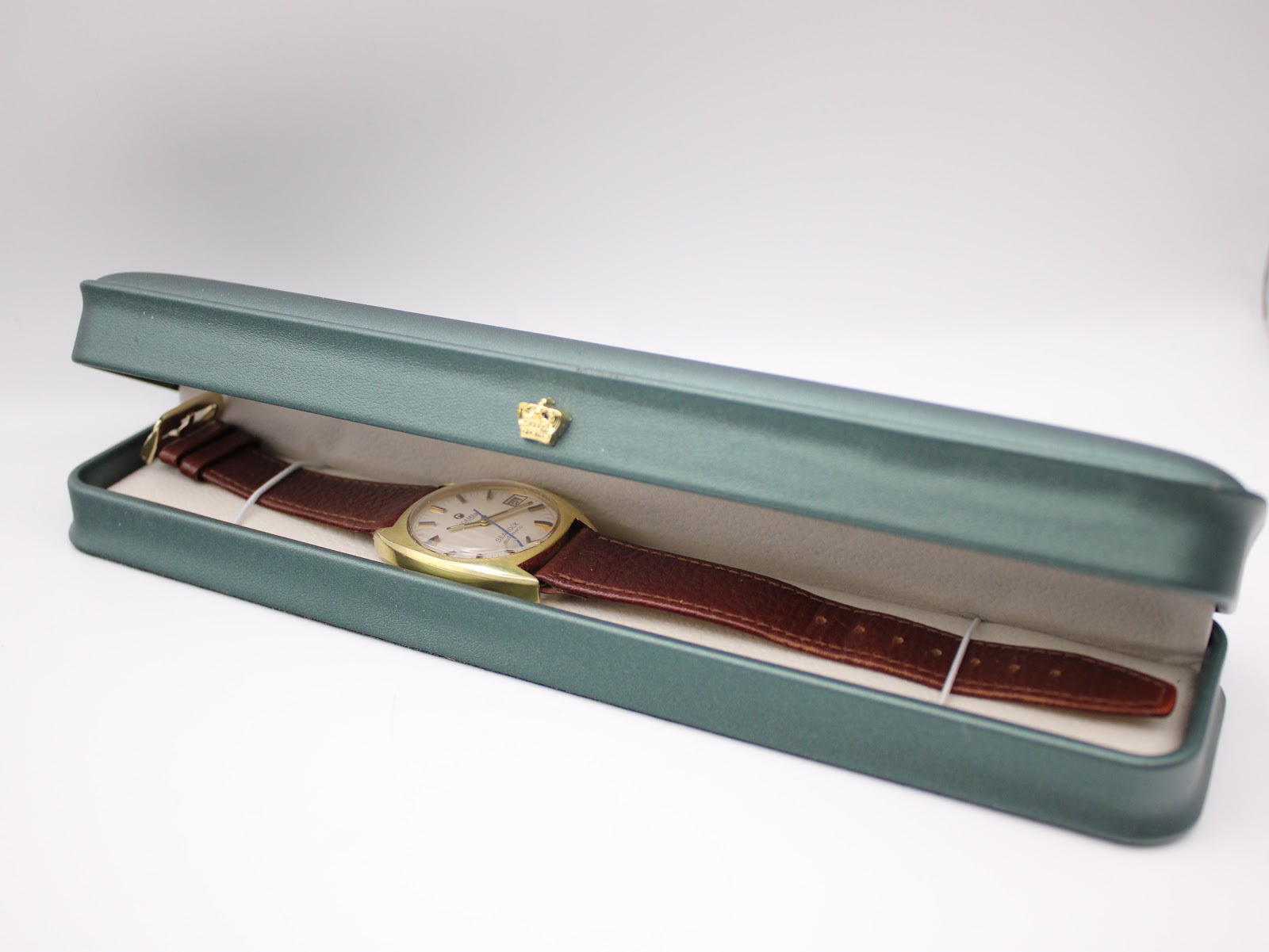 Roamer Searock watch laid inside a long, dark green presentation box.