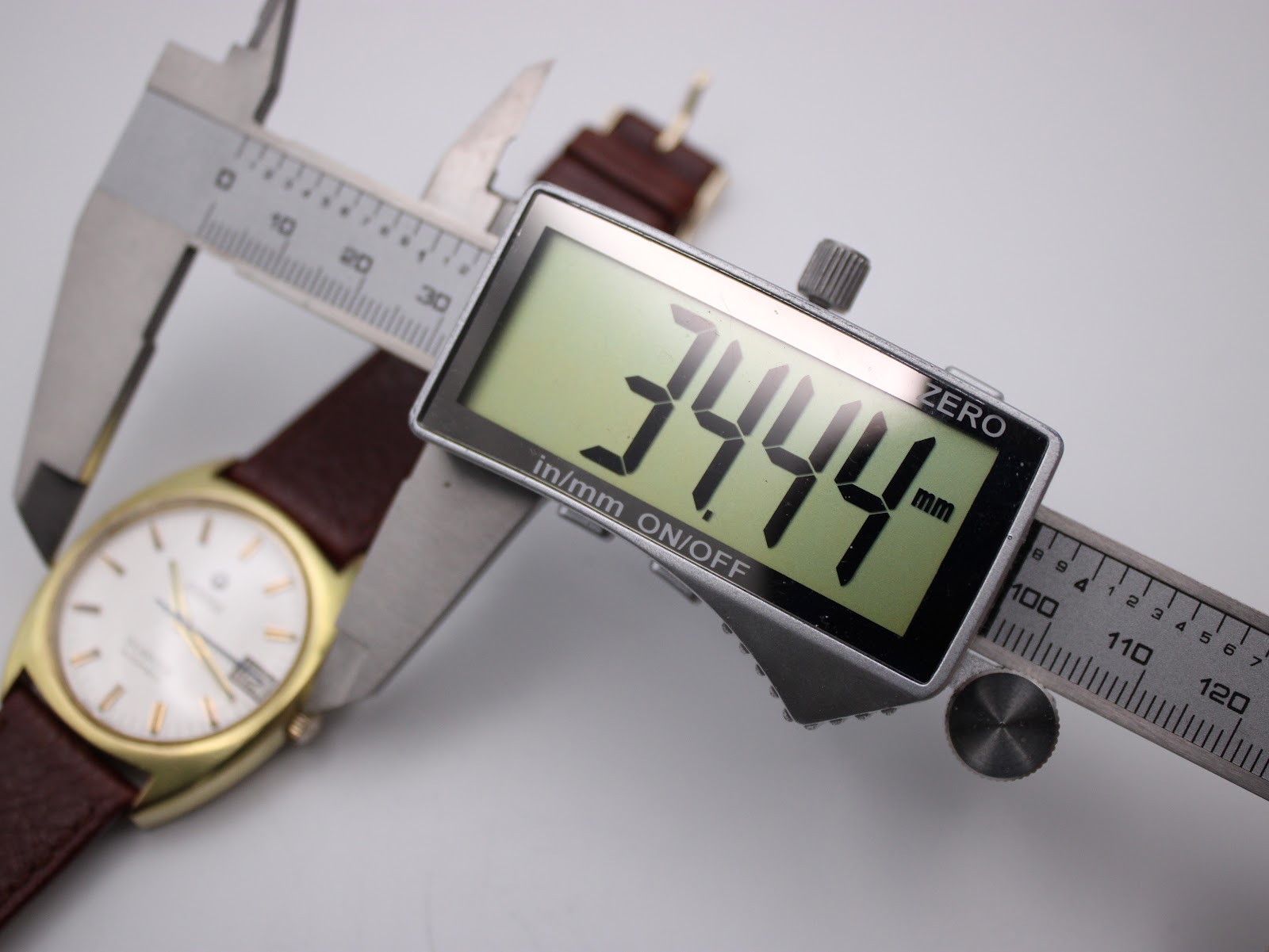 Digital caliper measuring the watch case diameter at 34.44mm.