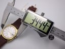 Digital caliper measuring the watch case diameter at 34.44mm.