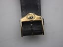 Back view of the entire Gucci 4500 M watch, showing the gold-tone case back and the 'GENUINE LEATHER' marking on the strap lining.