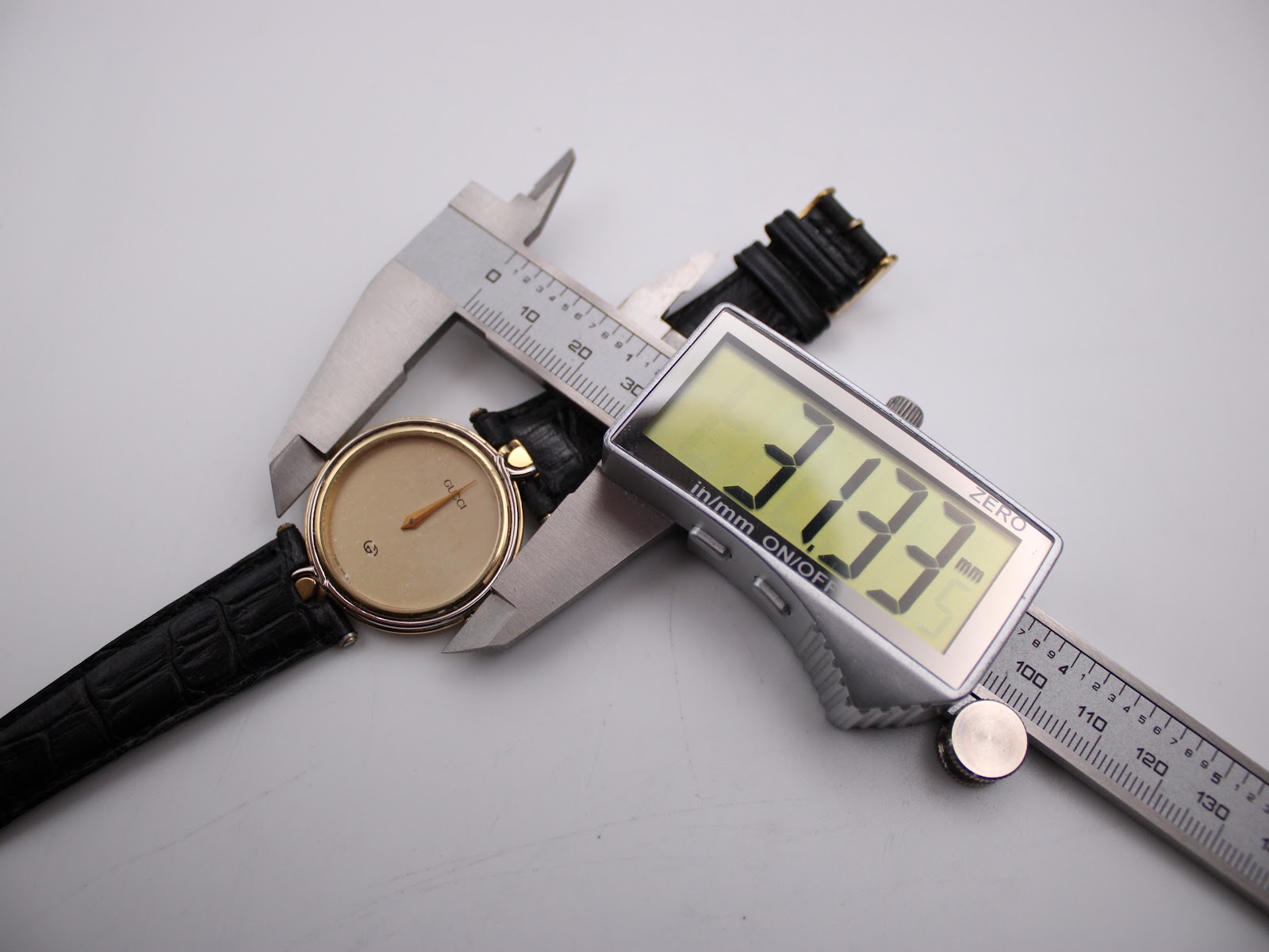 Gucci 4500 M watch being measured by a digital caliper, displaying a case diameter of 33.33mm.