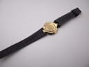 The Gucci 4500 M watch placed in a green presentation box, with the black leather strap visible.