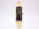 Front view of the vintage gold-plated Seiko 1520 watch with a black dial and gold bracelet, displayed on a clear stand.