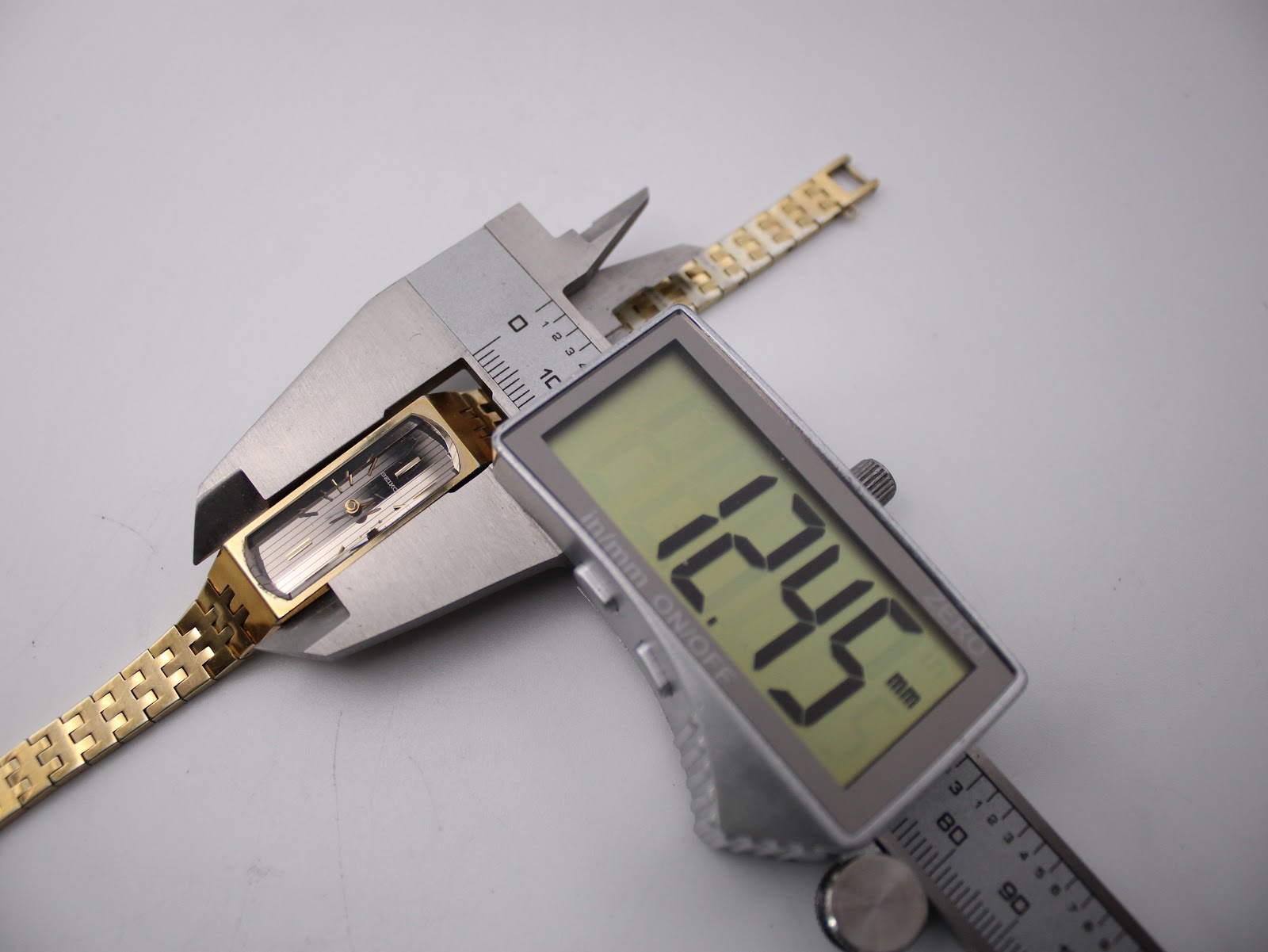 Digital caliper measuring the width of the Seiko watch case, displaying 12.45mm.
