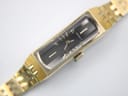 Angled close-up of the Seiko watch, focusing on the rectangular gold-plated case and the detailed black dial.