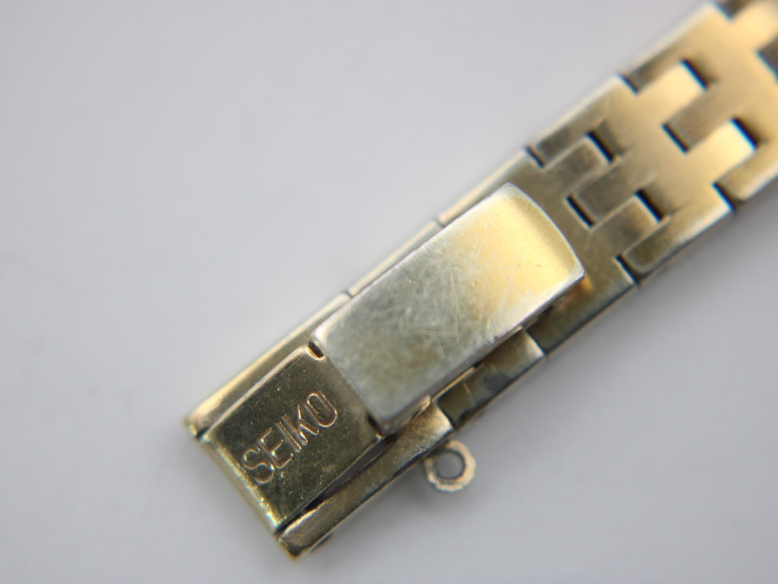 Detail shot of the gold-tone steel bracelet's folding clasp, clearly showing the 'SEIKO' signature.